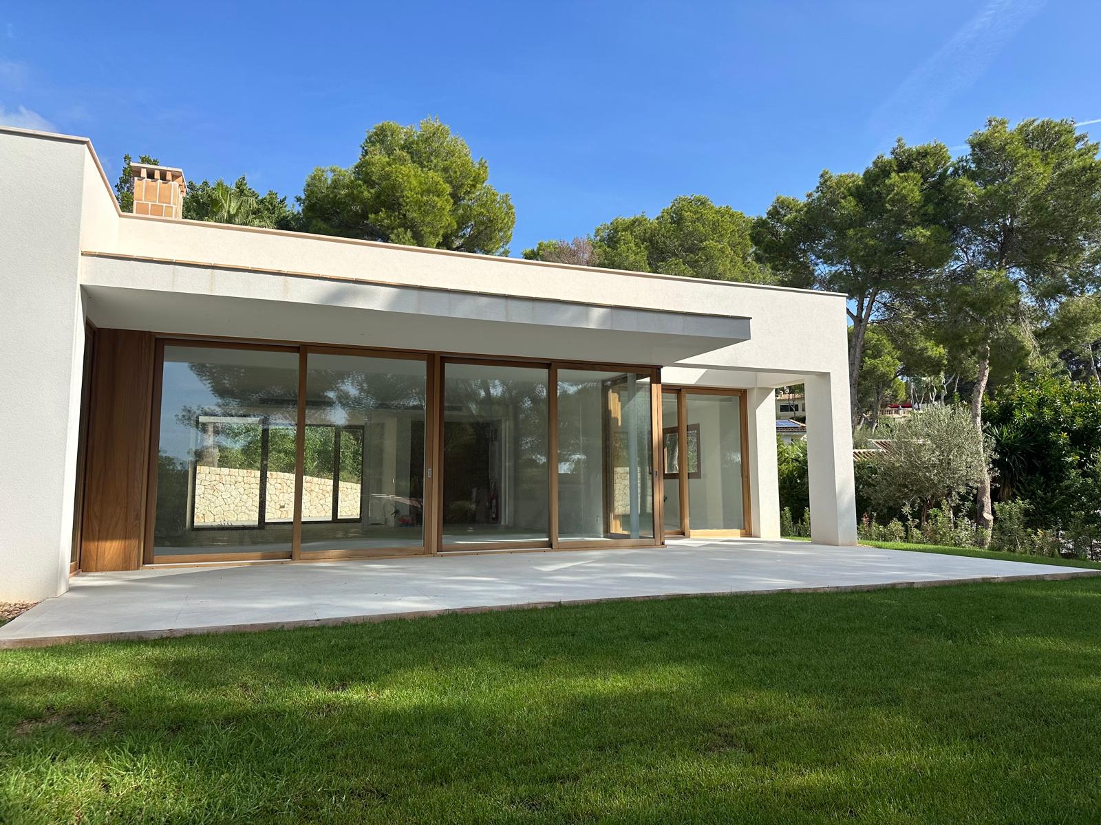 Private villa exterior with glass façade and garden lawn